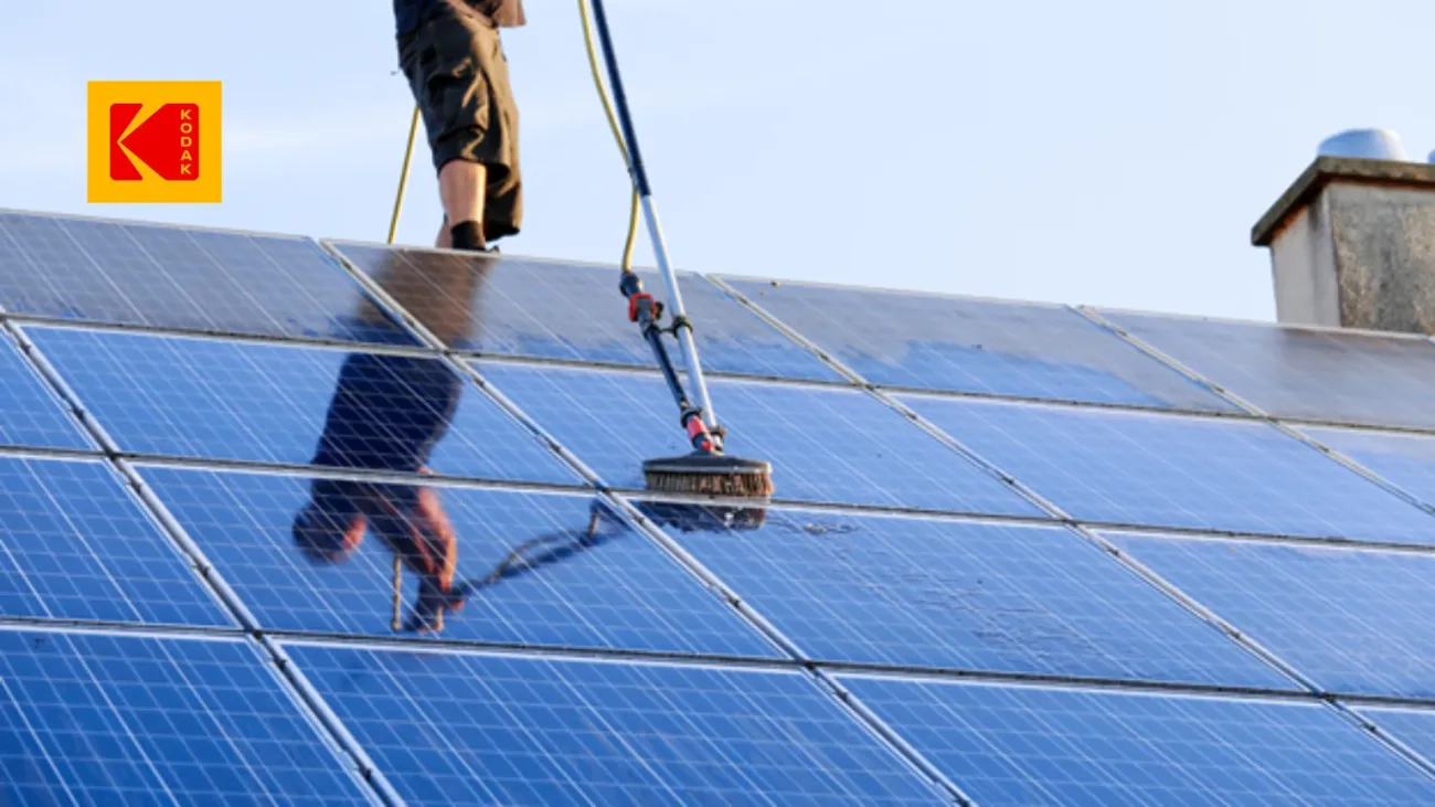 Une personne nettoie un panneau solaire avec une brosse de nettoyage solaire.